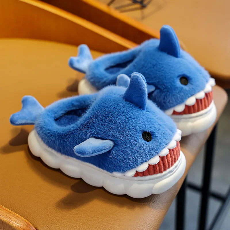 Pair of blue shark-shaped slippers on a wooden surface