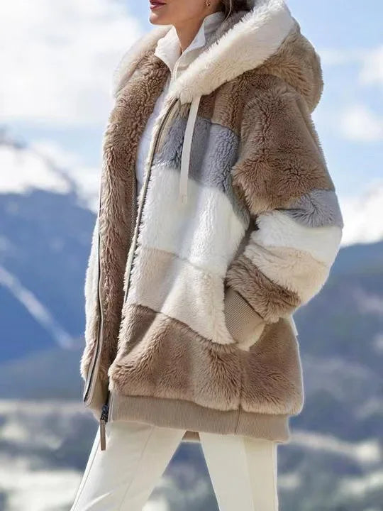 Person wearing a fluffy brown jacket with a mountainous background