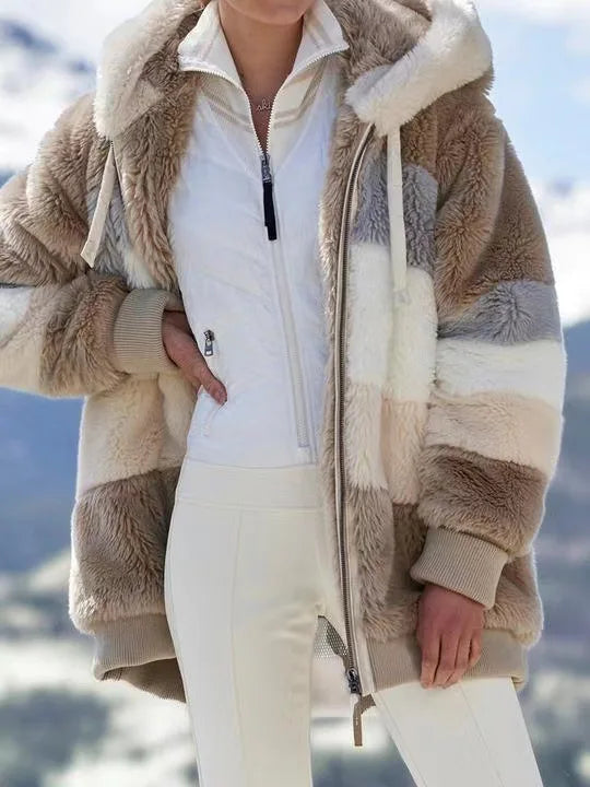 Person wearing a beige and white sherpa-lined jacket with a mountainous background