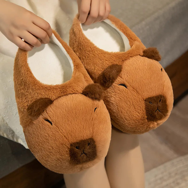 Pair of brown bear-shaped slippers held by a person.