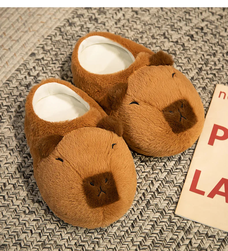 Pair of brown bear-shaped slippers on a textured surface with a book partially visible.