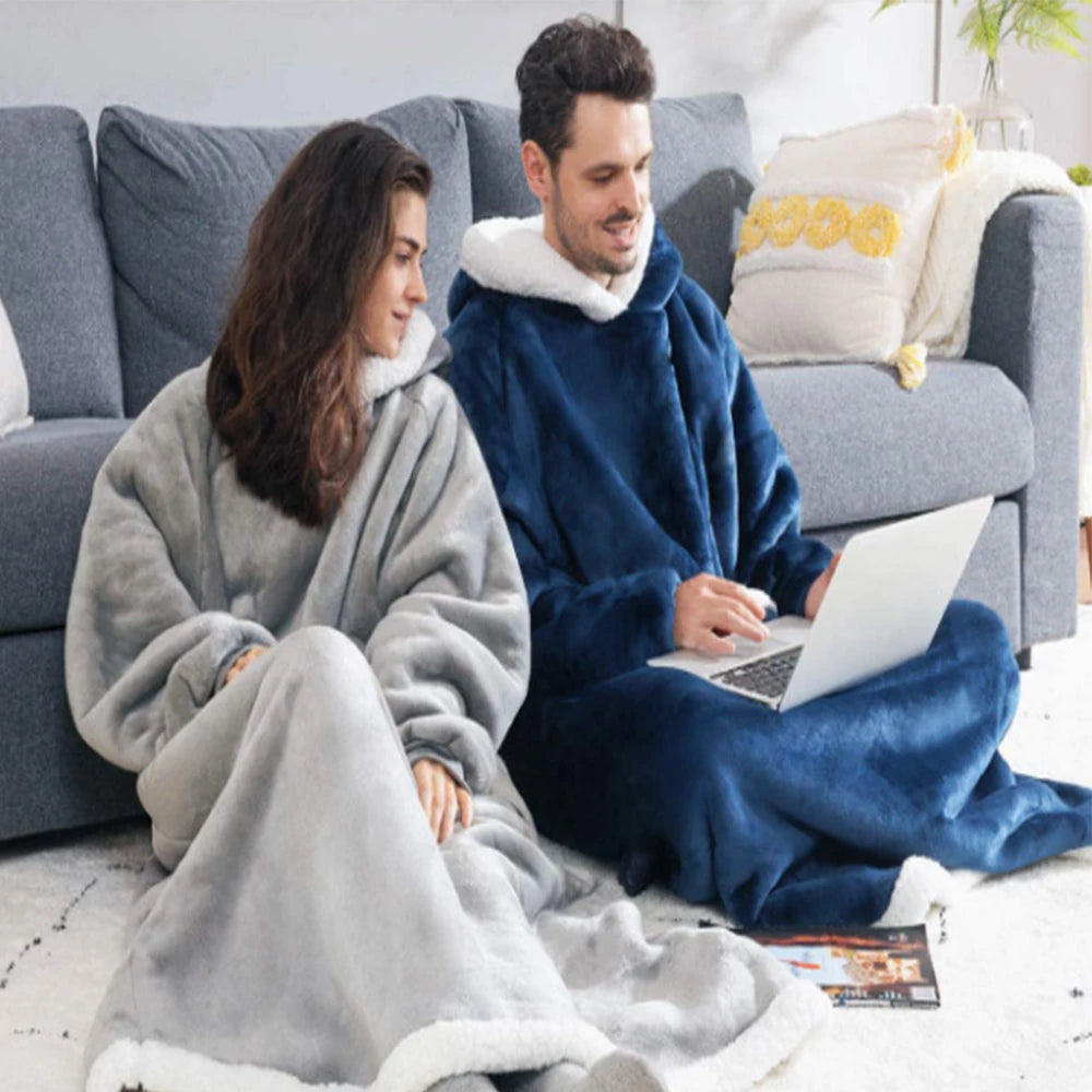 Two people sitting on a couch using a laptop, wrapped in cozy blankets.