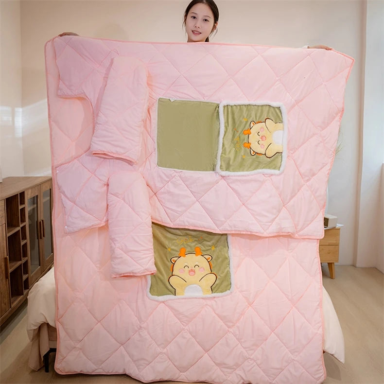 Pink quilt with cartoon patches held by a person in a room.